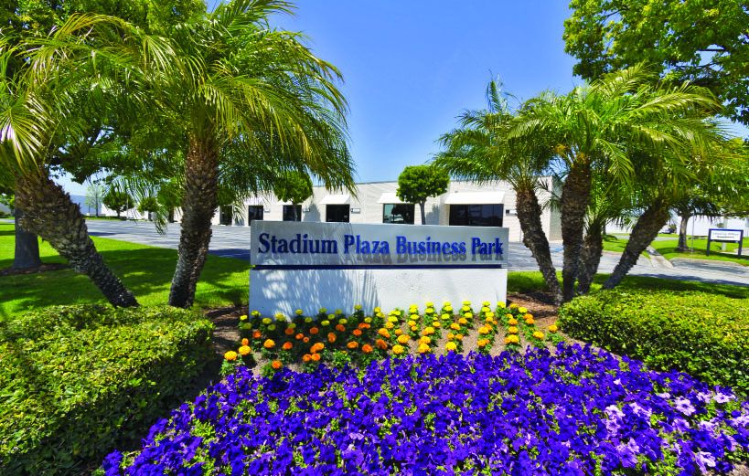 Stadium Plaza Business Park monument sign framed by palm trees and flowering landscaping